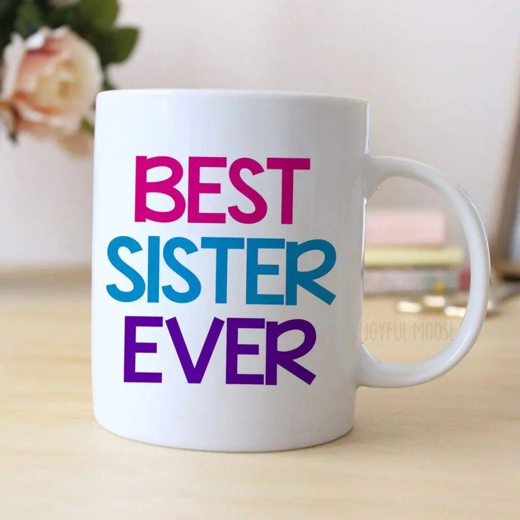 White coffee mug with colorful text "BEST SISTER EVER".