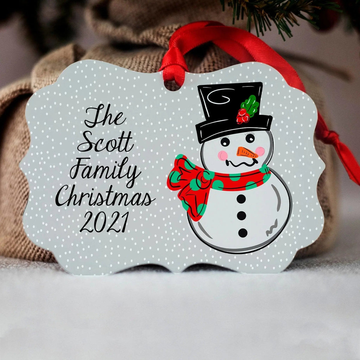 Personalized snowman Christmas ornament with red ribbon and text "She Scott Family Christmas 2021"