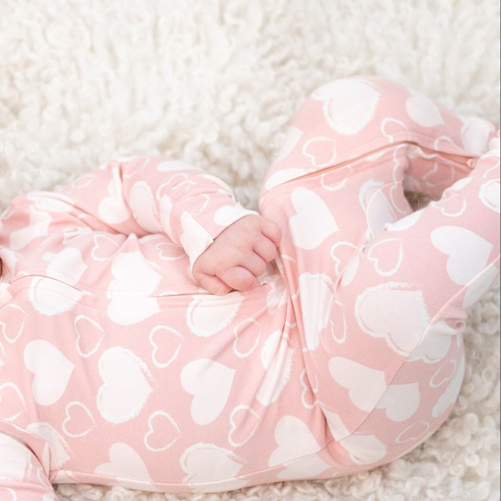 Pink heart-print convertible romper with long sleeves and front zip, close-up on legs