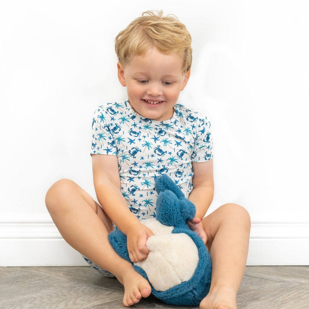 Boys short pajama set with white blue sea critter print, holding plush crab toy