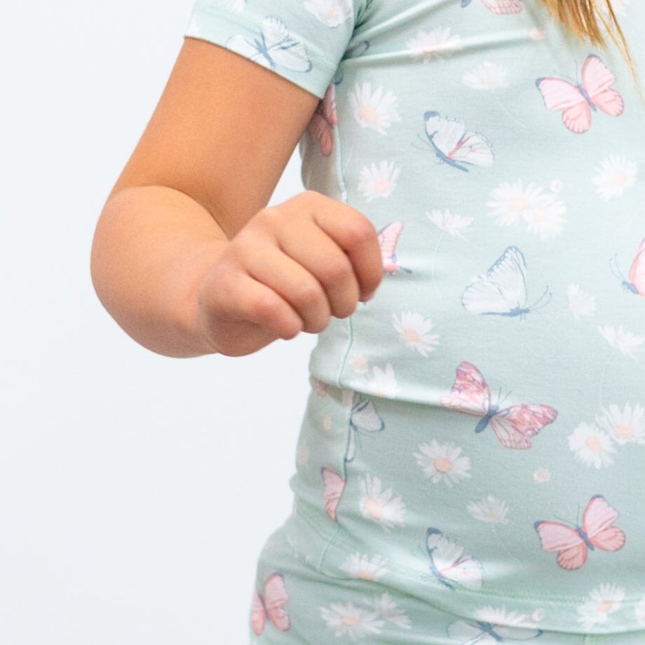 Close-up of mint girls pajama fabric with butterflies and daisies pattern