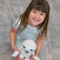 Girls mint short-sleeve pajama top with butterfly and daisy prints, holding a plush dog