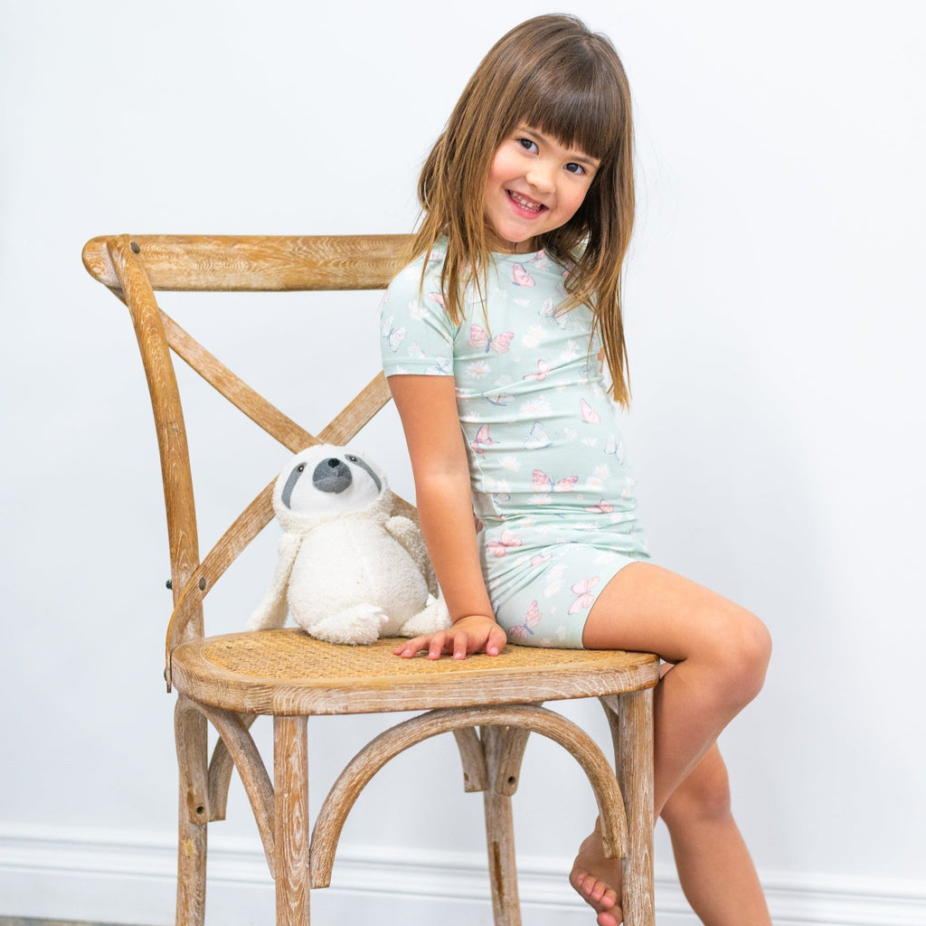 Girls mint printed pajama set with short sleeves and shorts while sitting on a chair