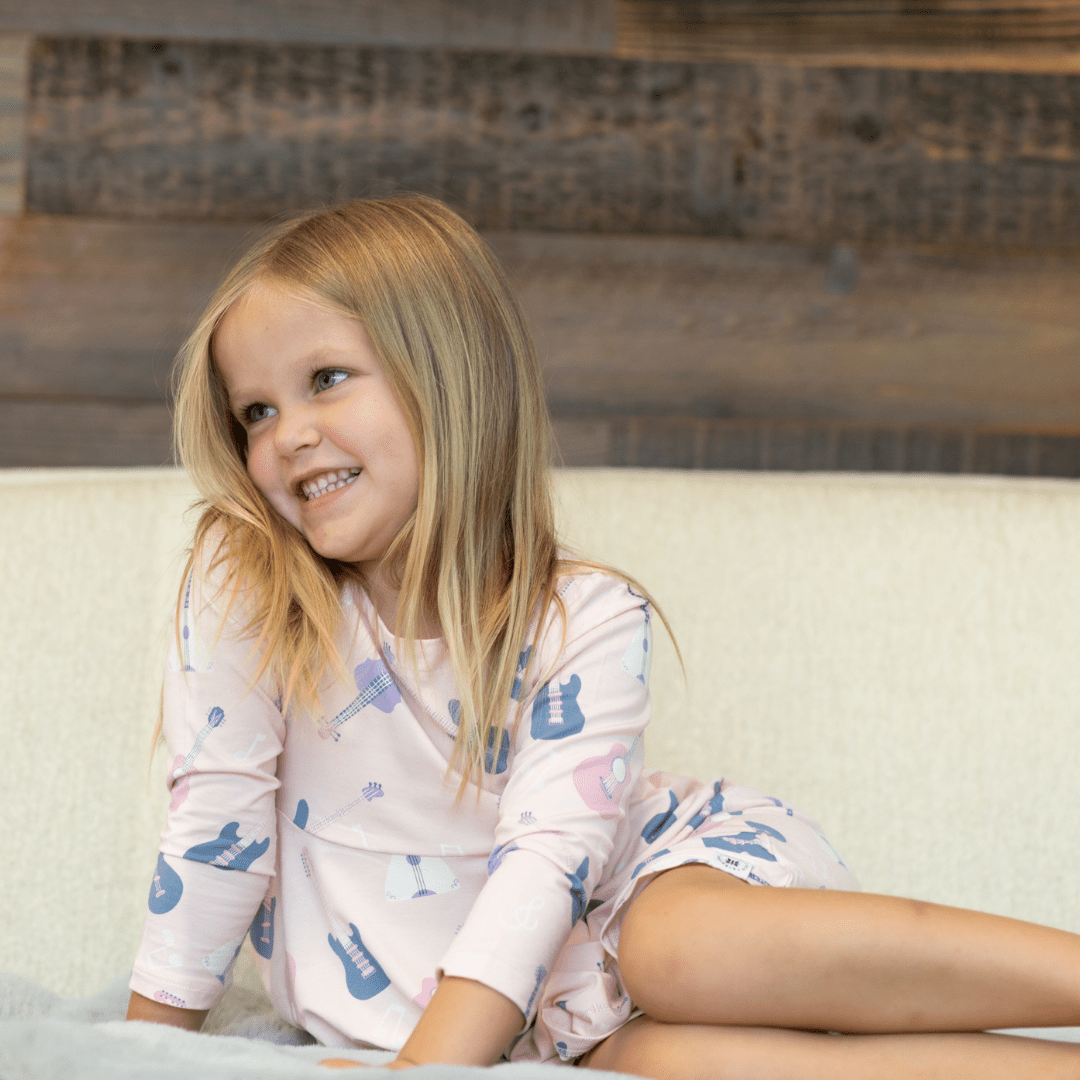 Girl's swirly dress in light pink with guitars and music icons, long sleeves