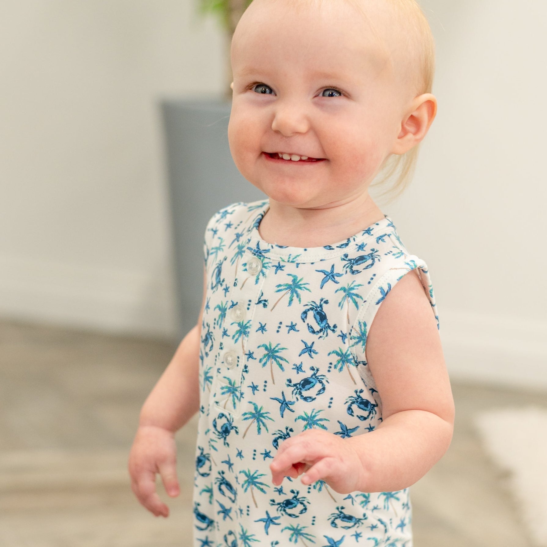 Baby in white blue crab and palm print tank romper, sleeveless close-up