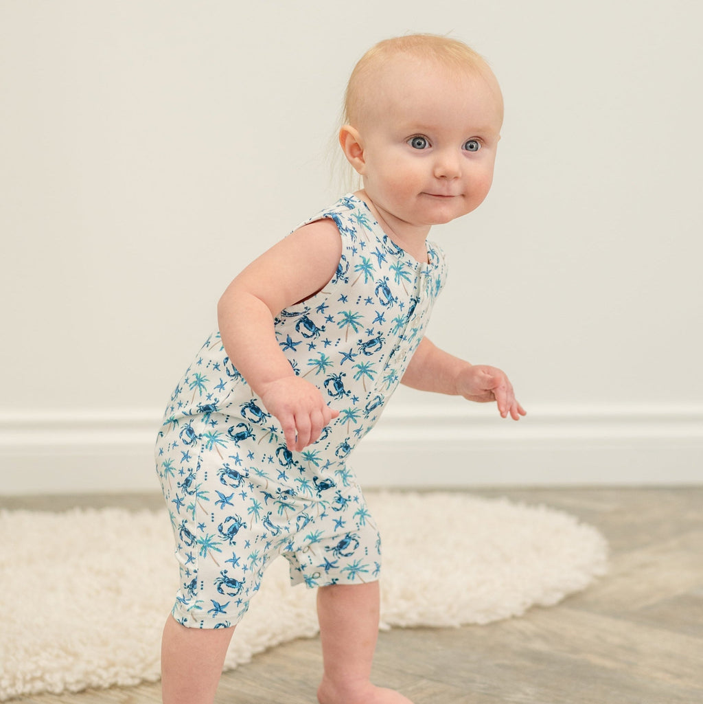 Baby in white blue crab and palm print tank romper, standing pose