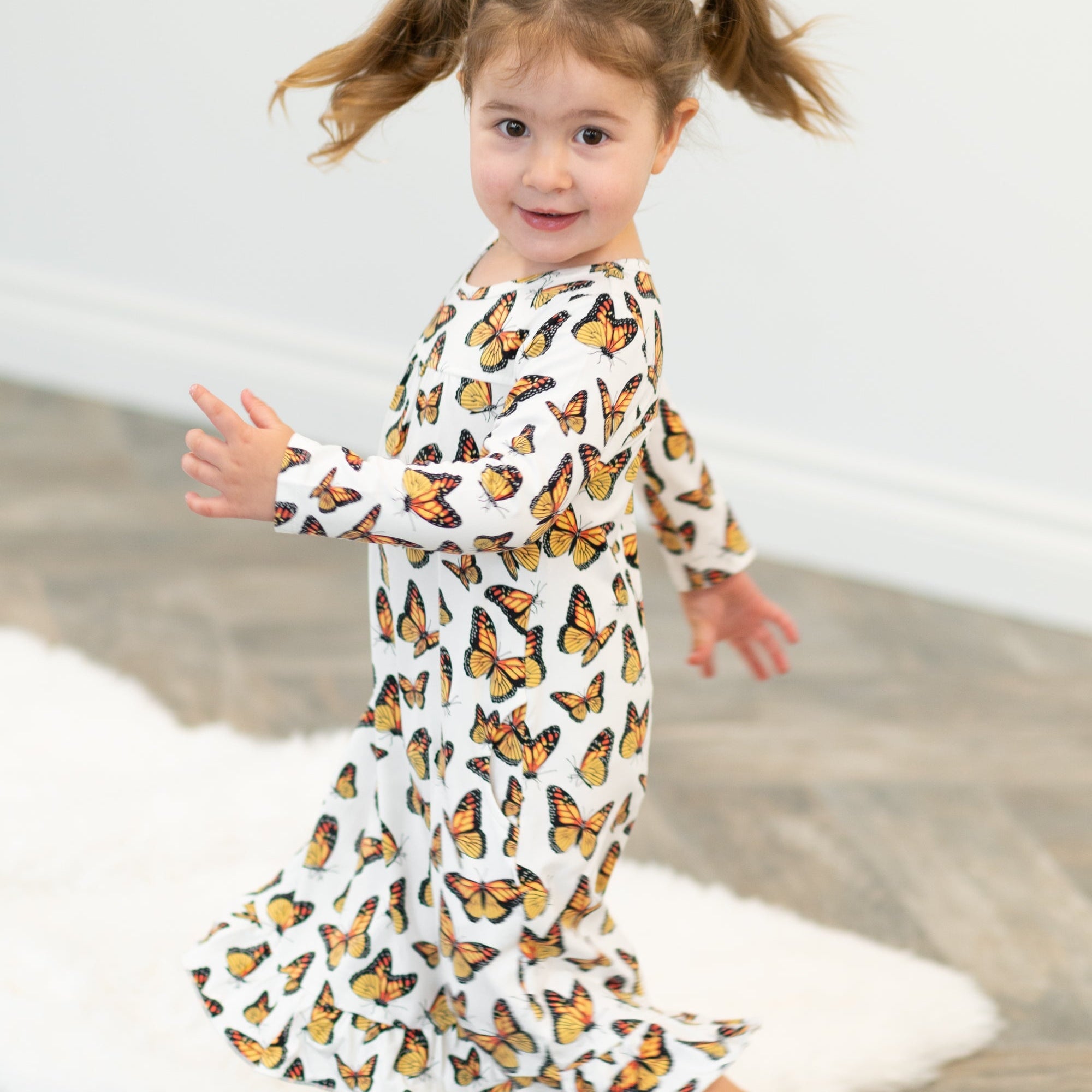 Girl's butterfly dress with long sleeves, round neck, and ruffled hem on white fabric