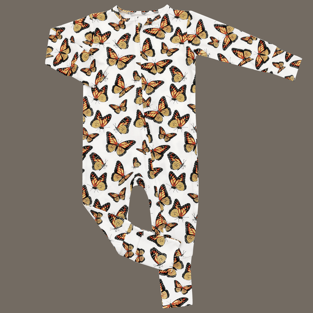 Butterfly-print footed romper in white with long sleeves and cuffed legs
