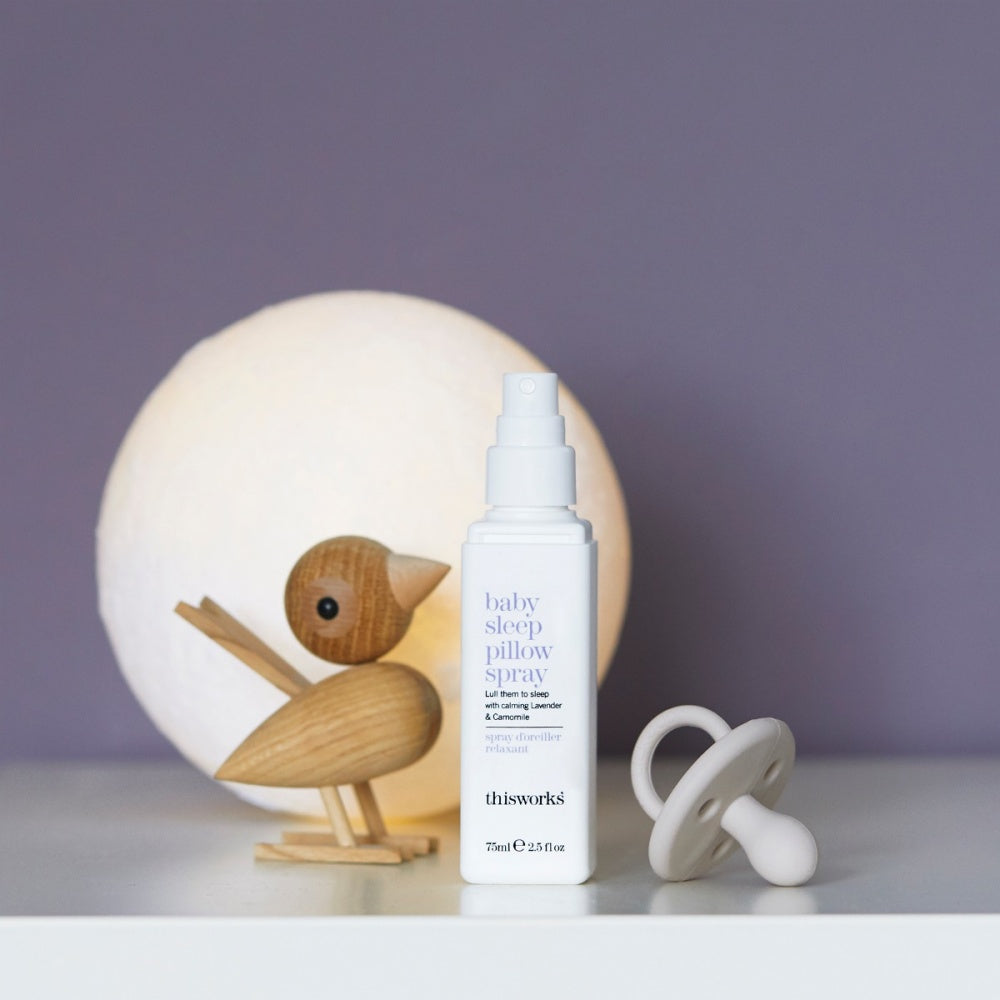 Baby sleep pillow spray bottle with white pump beside plush bird decor