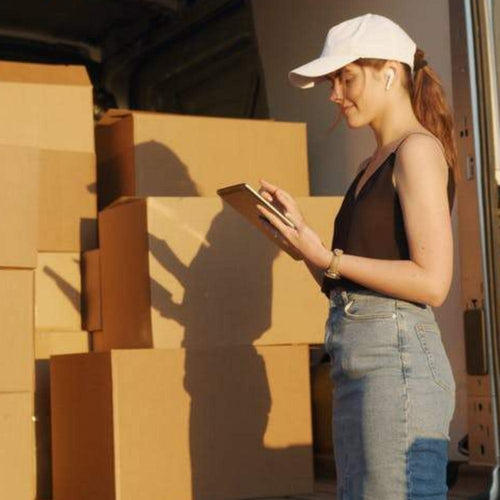 Reshipping fee: woman in white cap and dark tank next to shipping boxes
