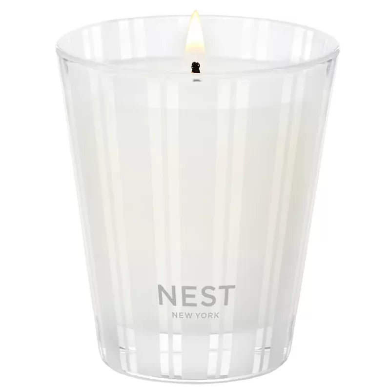 White ribbed candle jar with NEST New York label and lit wick