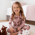 Girl wearing pink wild horse print pajama set with long sleeves and matching pants