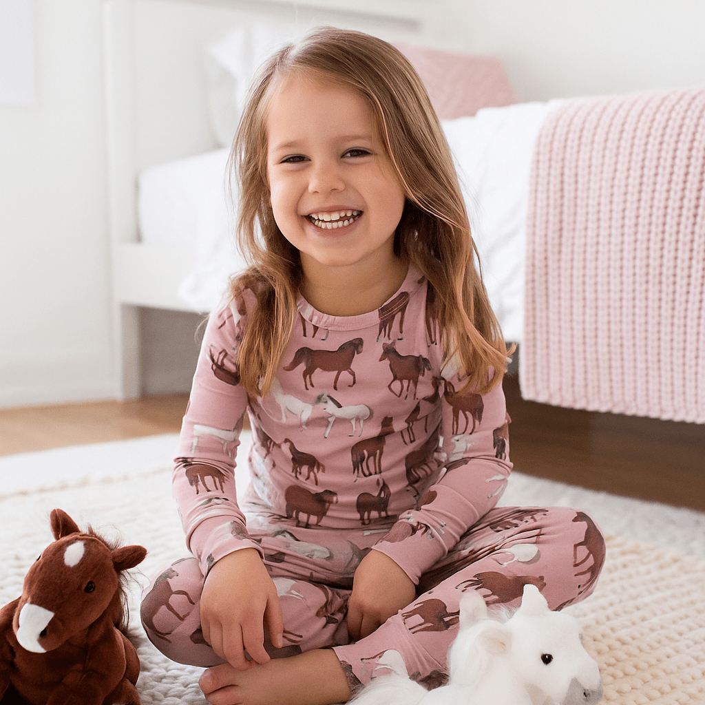 Girl wearing pink wild horse print pajama set with long sleeves and matching pants