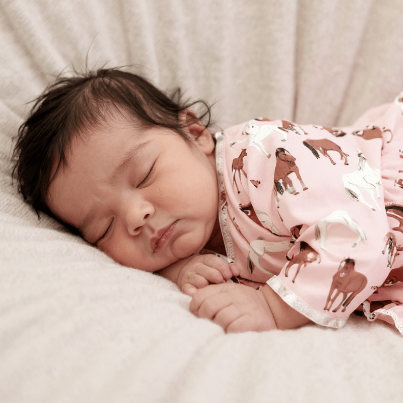 Pink horse-print ruffle gown with long sleeves, worn by a baby girl