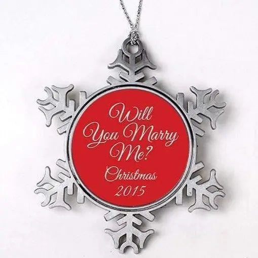Red round Christmas ornament with silver snowflake frame, “Will You Marry Me?” text