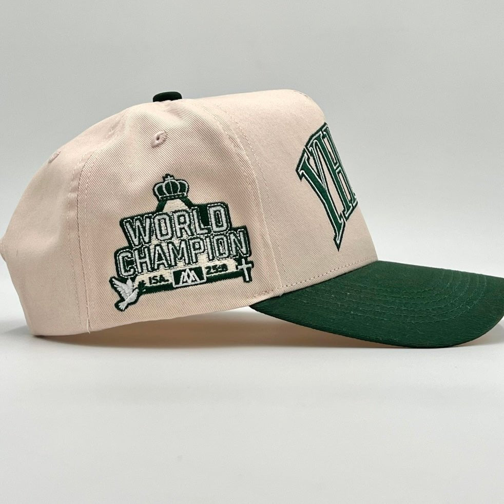 Cream snapback cap with World Champion emblem on side and dark green brim