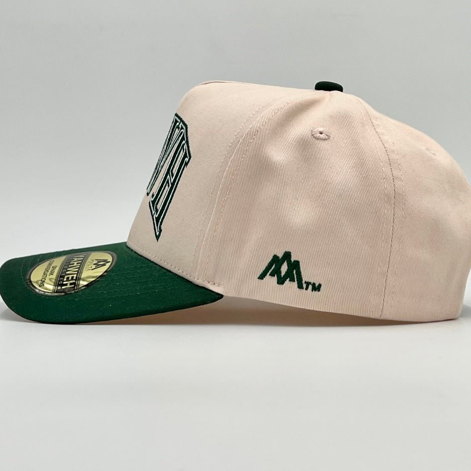 Cream snapback cap side view with dark green brim and small emblem patches
