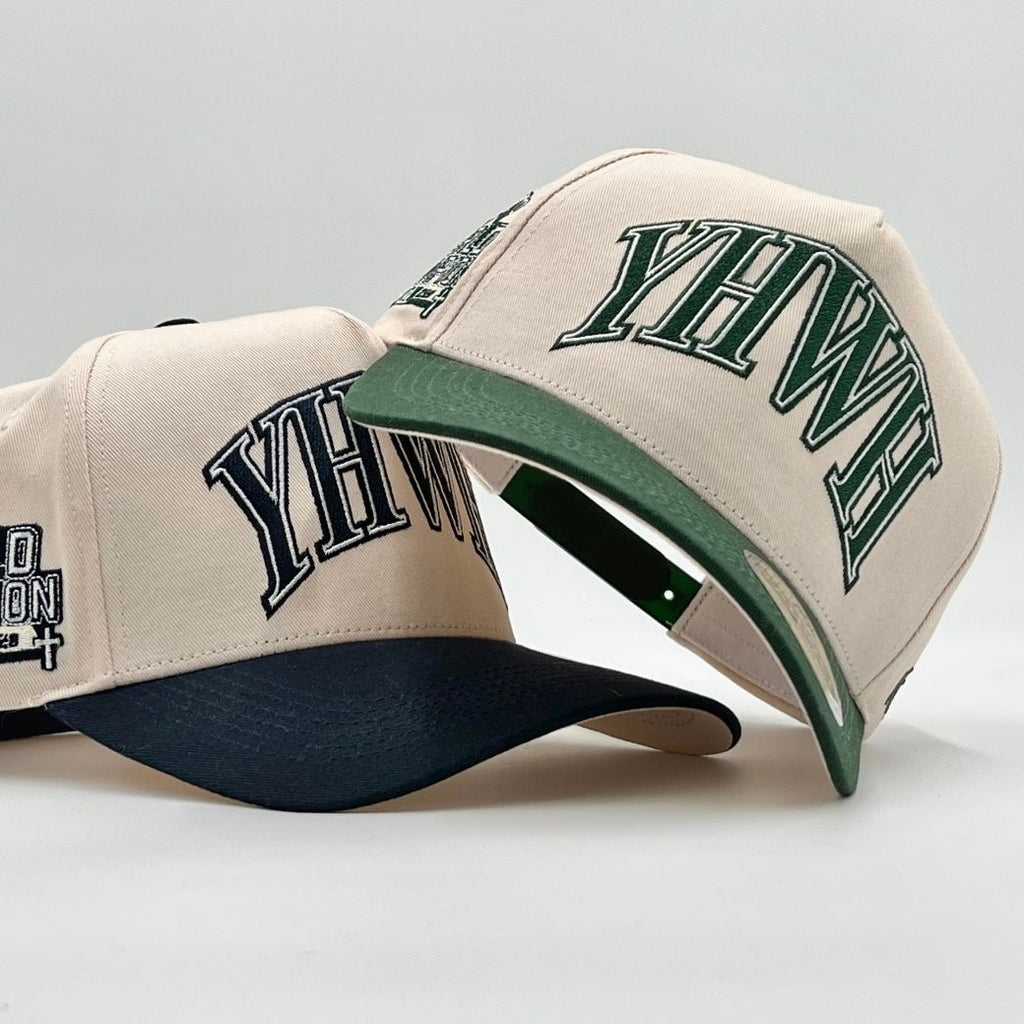 Two cream snapback caps with dark green brims showing YHWH side embroidery