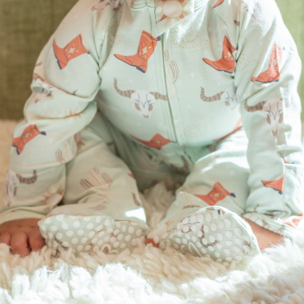 Light blue baby footie romper with cowboy boot and cactus print, zip front